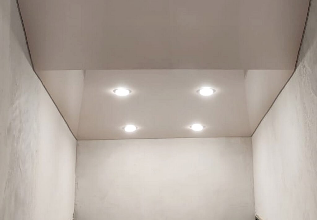 Глянцевый бежевый натяжной потолок на лестничном пролете