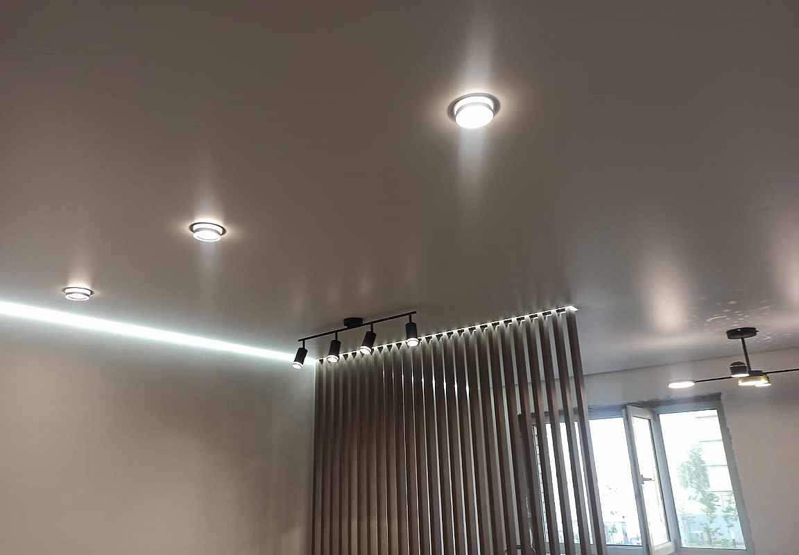 Точечные светильники в парящем матовом натяжном потолке.