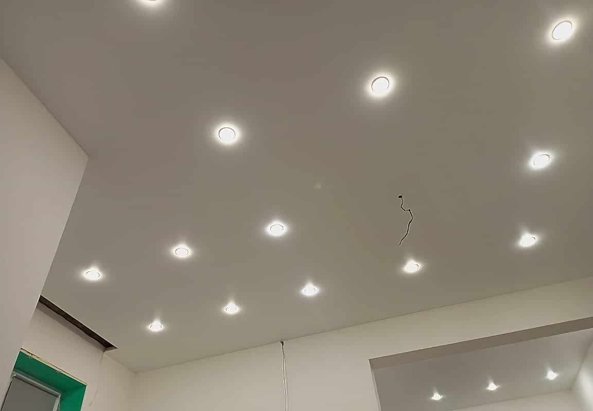 Белый матовый натяжной потолок с точечными светильниками в интерьере гостиной.