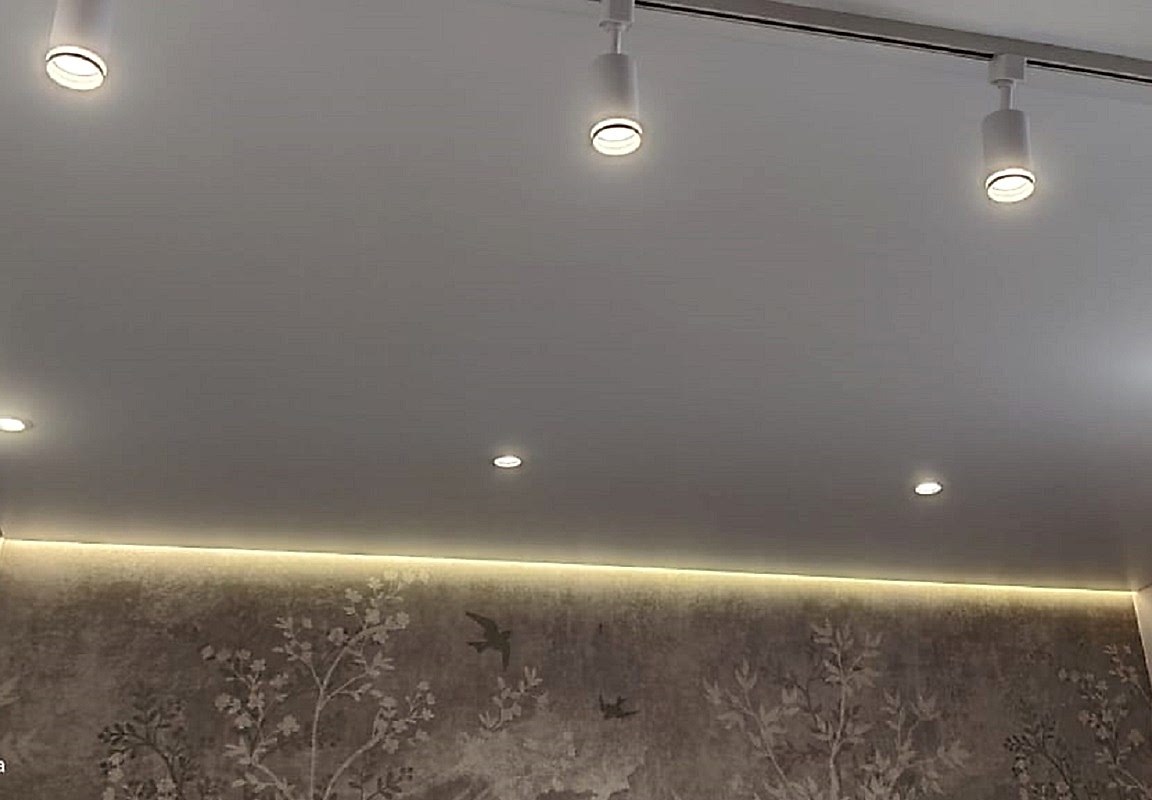 Парящий сатиновый натяжной потолок и точечные светильники в интерьере гостиной.