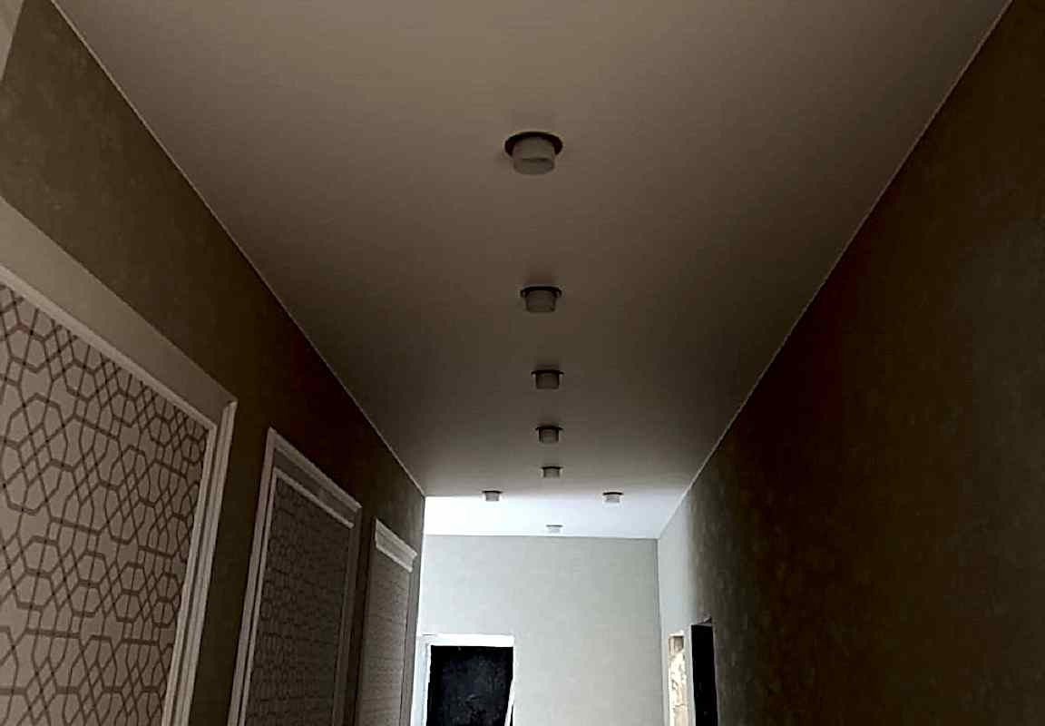 Матовый натяжной потолок и накладные светильники в коридоре.