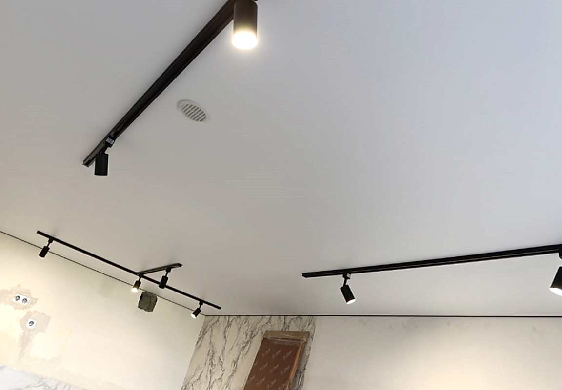 Натяжной потолок,накладные треки в интерьере гостиной.