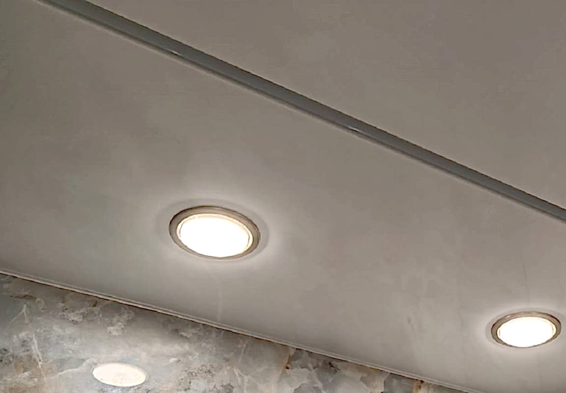 Серебристые светильники и глянцевый потолок в ванной.