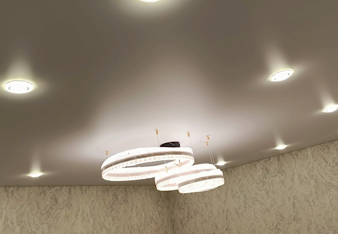 Точечные светильники с подсветкой кольца в сатиновом натяжном потолке в гостиной.